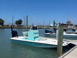 Turquoise and white fishing boat docked at marina in Port Aransas TX with outboard motor and center console