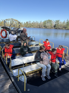 Airboat tour on calm waterway in Orange TX with passengers wearing life jackets