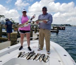 Successful fishing trip in Gulf Shores AL showing redfish and speckled trout catch on boat deck at marina
