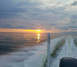 Boat wake trailing behind fishing vessel at sunset in Gulf Shores AL waters