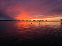 Stunning sunset over calm lake waters in Elma New York with vibrant orange and purple sky reflections