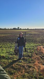 Hunter with rifle standing in grassy field with rocky terrain in Elma New York
