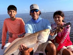 A group of 3 people fishing for a single redfish in Texas City