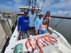 Red snapper fishing catch displayed on boat deck in Gulf Shores AL with fishing rods and marina dock visible
