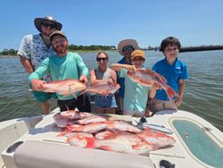 Successful red snapper fishing trip in Gulf Shores AL with large catch displayed on boat deck