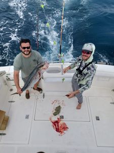 Deep sea fishing catch displayed on boat deck in Fort Walton Beach FL with fishing rods and churning ocean water in background