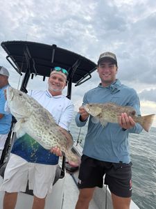 Two anglers displaying caught gag grouper on fishing boat in Riverview FL