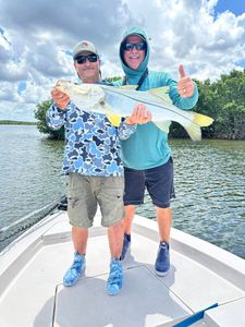Two anglers holding a caught snook on fishing boat in Riverview FL
