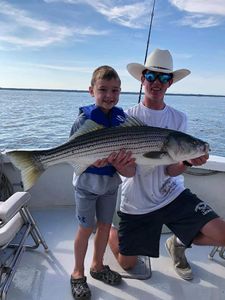 Striped bass caught by two people fishing in Cape Cod