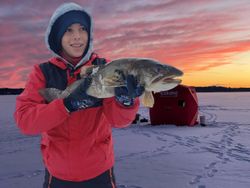 A single fisherman in Saranac Lake, holding a 16-inch fish