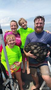 Family fishing trip in Brooksville FL with mesh bag full of fresh catch on boat deck
