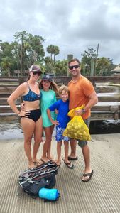 Family fishing trip on wooden dock in Brooksville FL with yellow mesh bag of catch