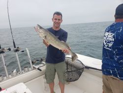 Single angler reeling in a large fish at the lakeside in Marblehead