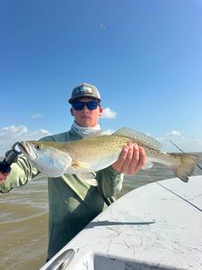 Angler holding freshly caught speckled trout while fishing in Matagorda TX