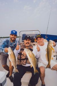 Three anglers displaying caught redfish on fishing boat in Elmendorf TX