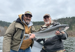 Two anglers proudly displaying a large salmon catch while fishing in Grants Pass, Oregon