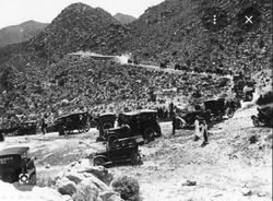 Historic black and white photograph showing vintage military vehicles and aircraft in desert mountain terrain near Yuma AZ