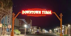 Downtown Yuma Arizona illuminated welcome arch at night with historic buildings and palm trees