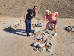 Tour visitors posing at historic cemetery with stone markers and crosses in Yuma Arizona desert landscape
