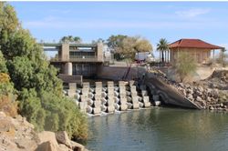 Historic dam and water control structure on river in Yuma Arizona with concrete spillway and control building