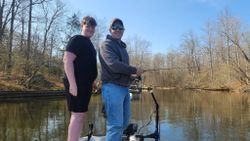 Two anglers posing with fishing equipment on calm water in King George VA