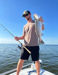 Photograph of a fisherman holding a spotted weakfish measuring 27 inches, taken in Manteo
