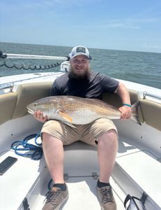 A man holding a large redfish in Manteo