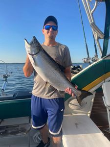 A fisherman proudly holding a large Chinook salmon in NY
