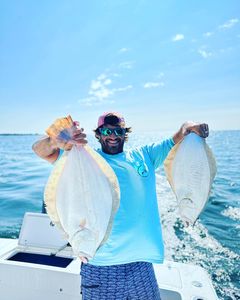 A person fishing for two winter flounder in Jamestown