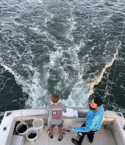 Fishing boat wake in Norfolk VA waters with two anglers fishing from stern