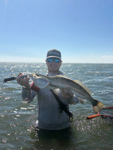 Angler holding large speckled trout while standing in water near Corpus Christi TX