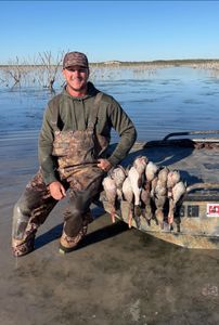 Successful duck hunting trip displaying multiple harvested waterfowl near boat in Corpus Christi TX