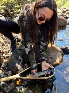 Freshly caught fish being held in landing net over rocky stream in Newport PA