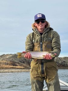 Angler holding freshly caught trout while standing in boat on river near Newport PA