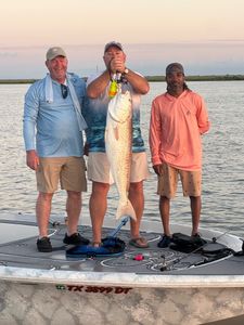 Three people fishing on a bridge in Bridge City