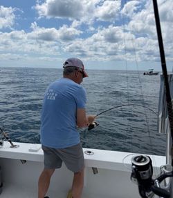 Angler fishing from boat deck in Morehead City NC waters with rod bent indicating fish on line