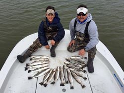Two anglers fishing on the banks of a river in TX