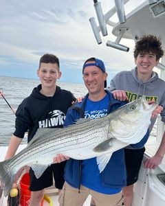 A fisherman holding a large striped bass in Middletown Township.