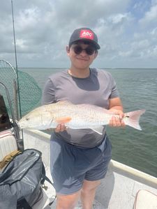 Bright catch of a hefty redfish on calm waters.