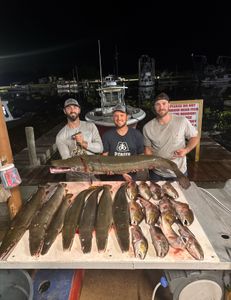 Three anglers with fishing rods stand in a scenic location in Lafitte