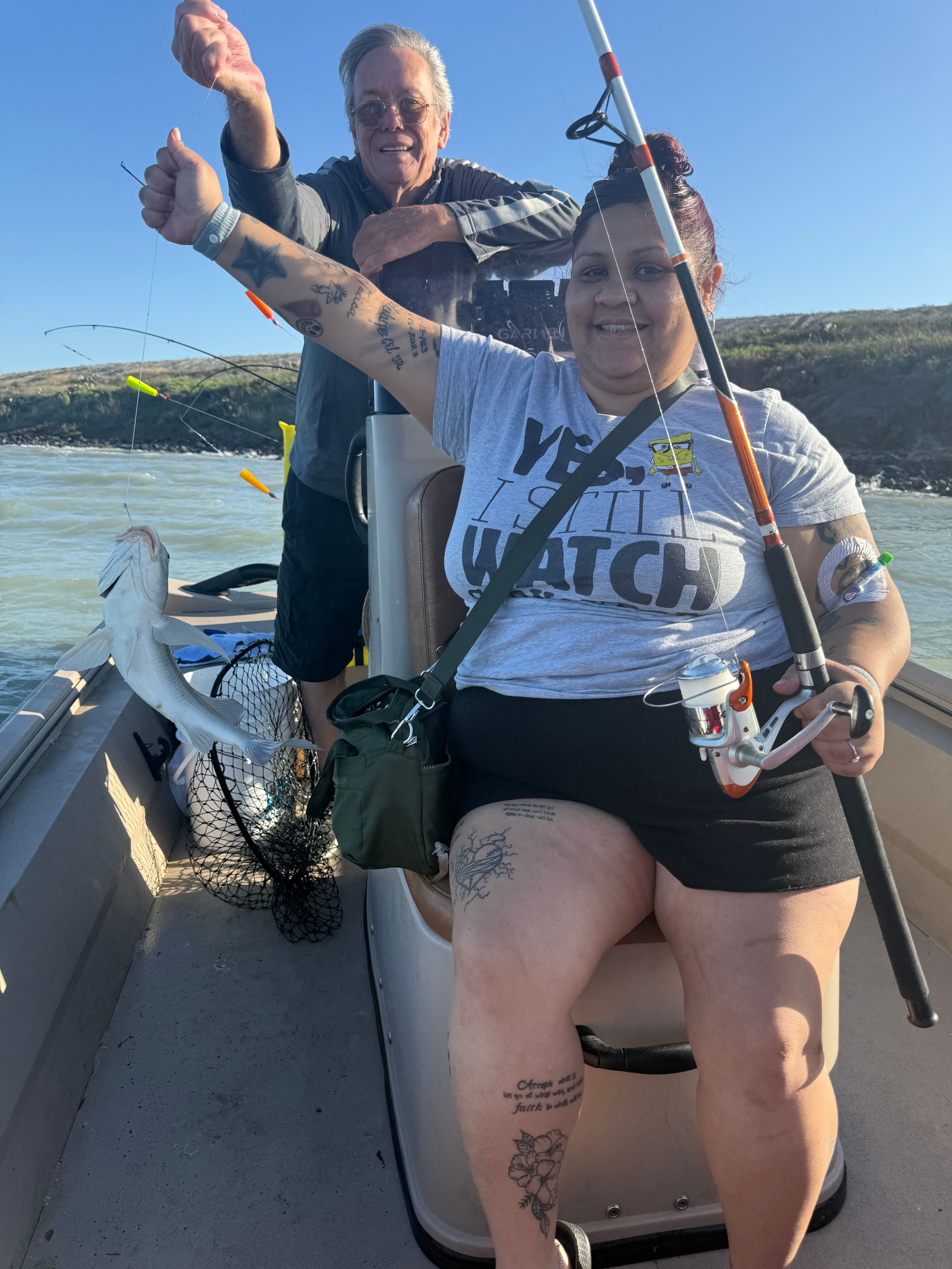 Fishing boat with caught fish being held up and fishing net visible on deck