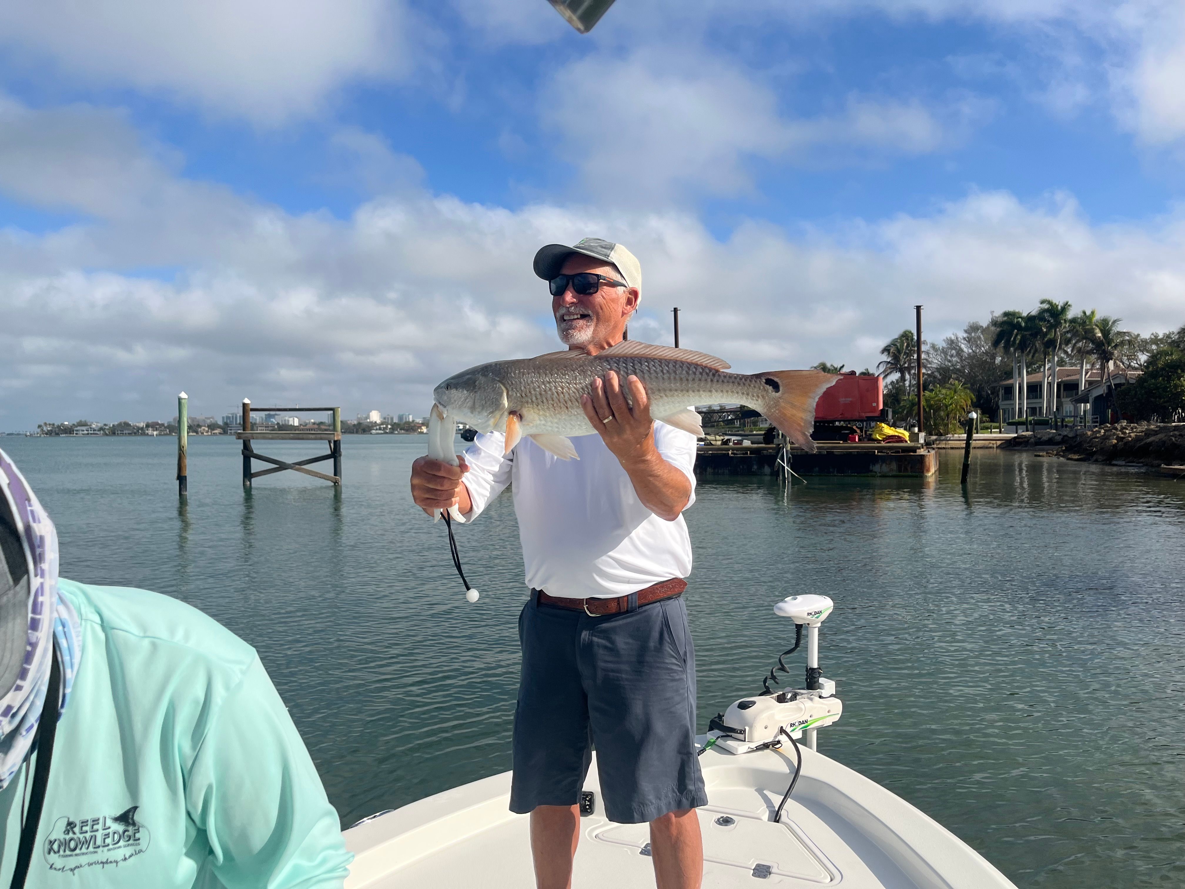 Angler holding freshly caught redfish on boat in calm waters
