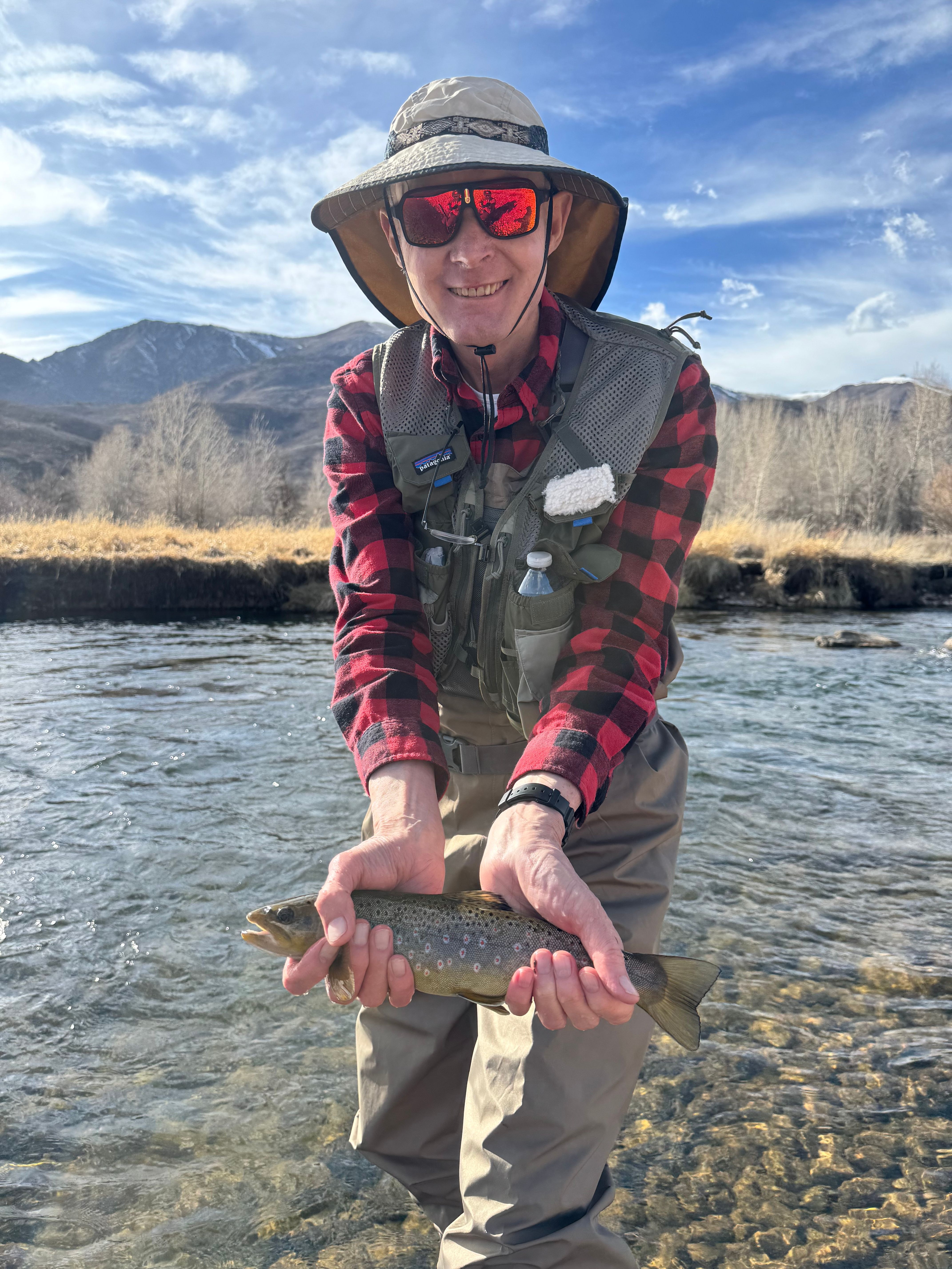 Angler holding a freshly caught brown trout by a lake