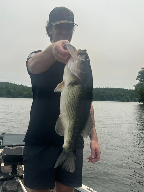 Angler holding large bass fish caught while fishing on lake