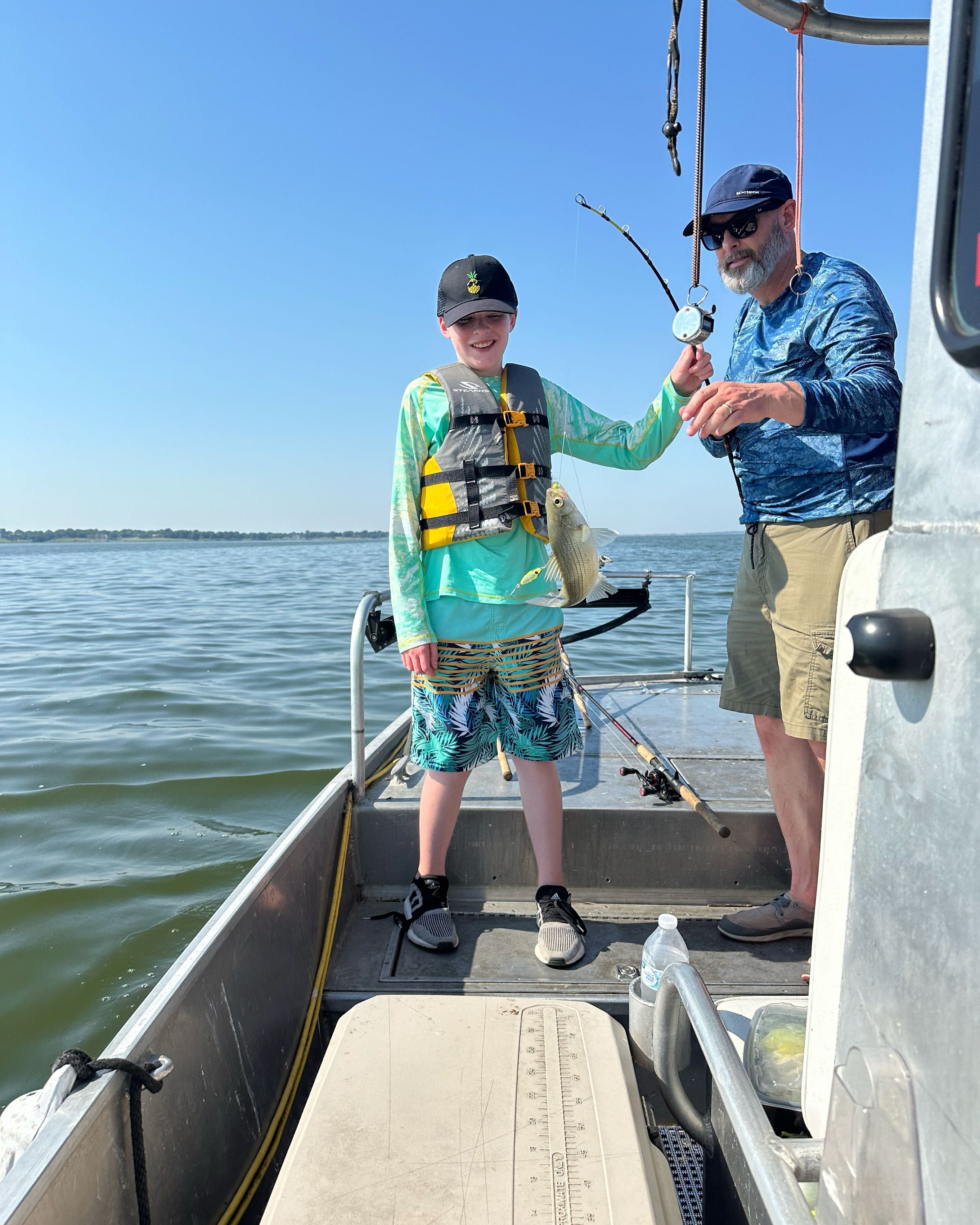 A person holding a white bass fish catch.