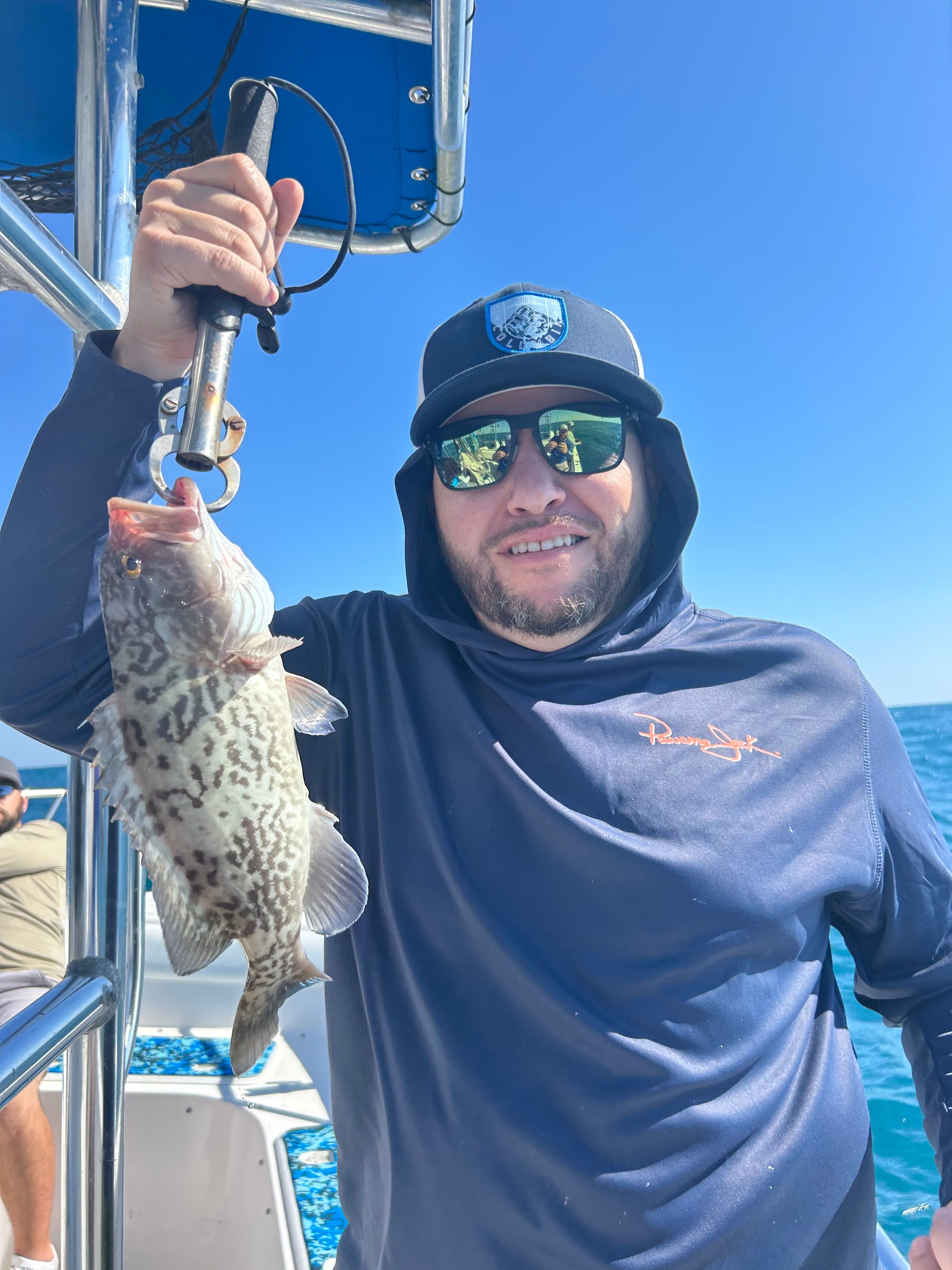 Freshly caught gag grouper being held on fishing boat with ocean in background