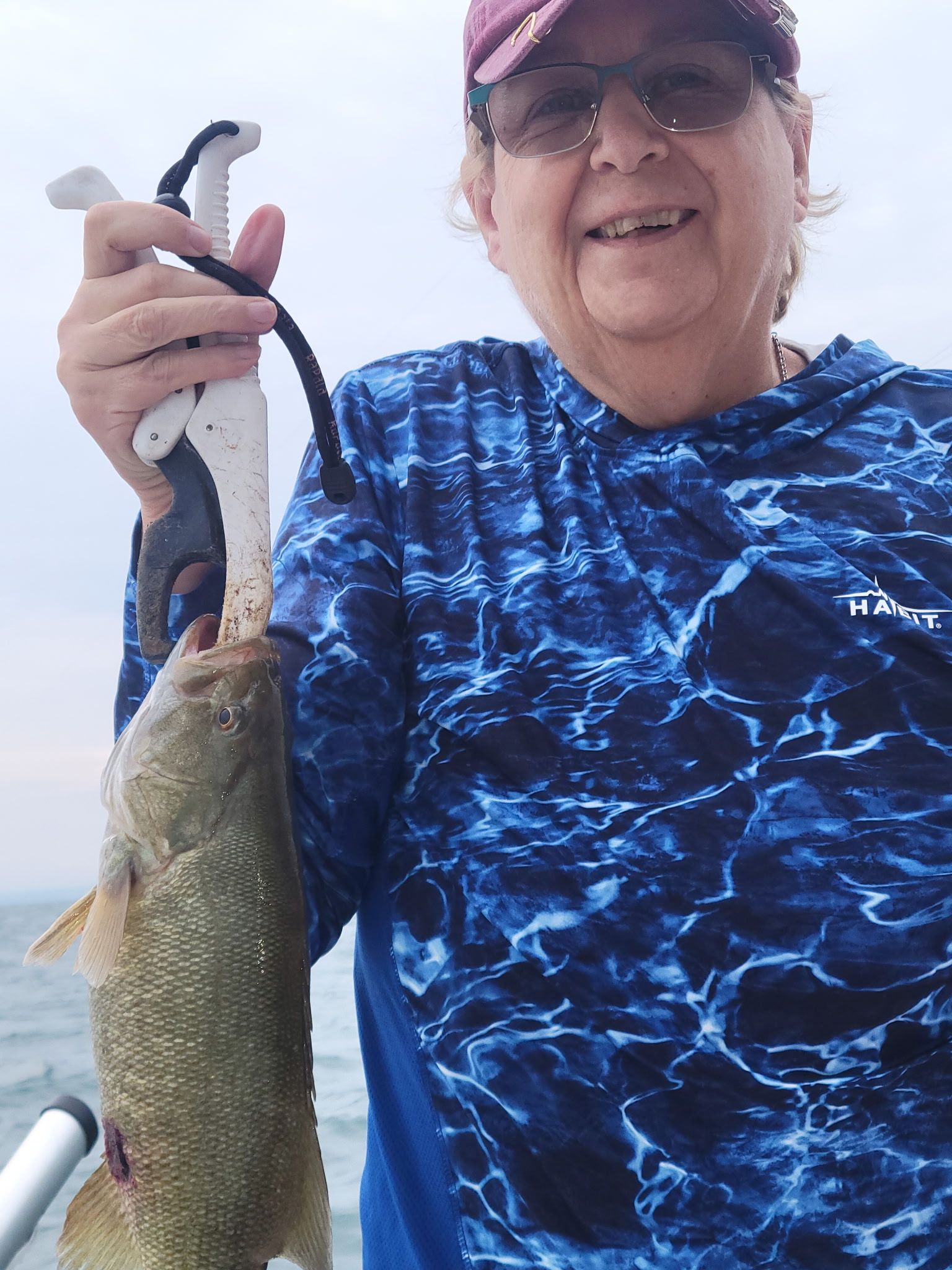 Angler holding freshly caught smallmouth bass on fishing boat outdoors