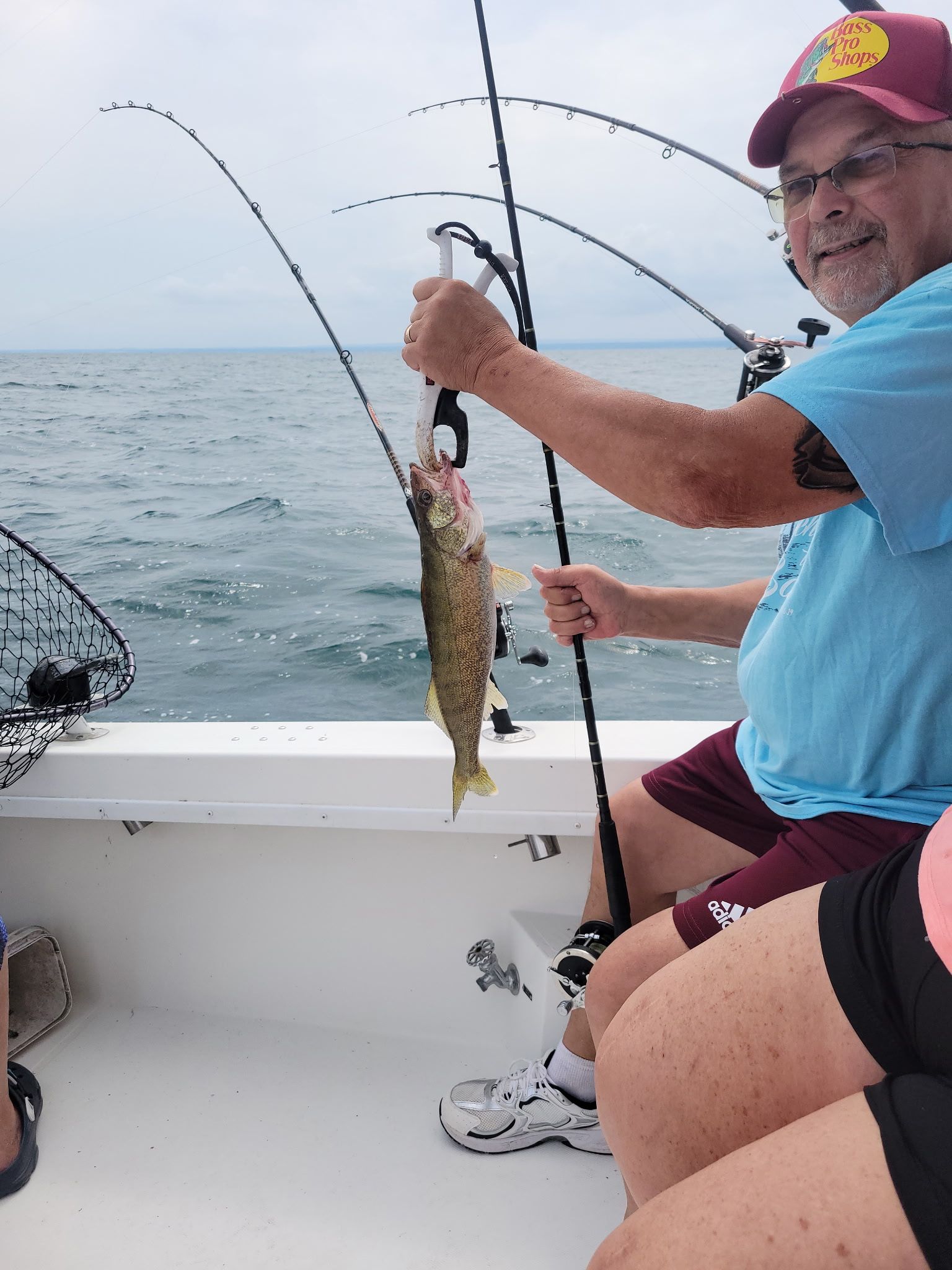 Freshly caught walleye being held up on fishing boat over open water