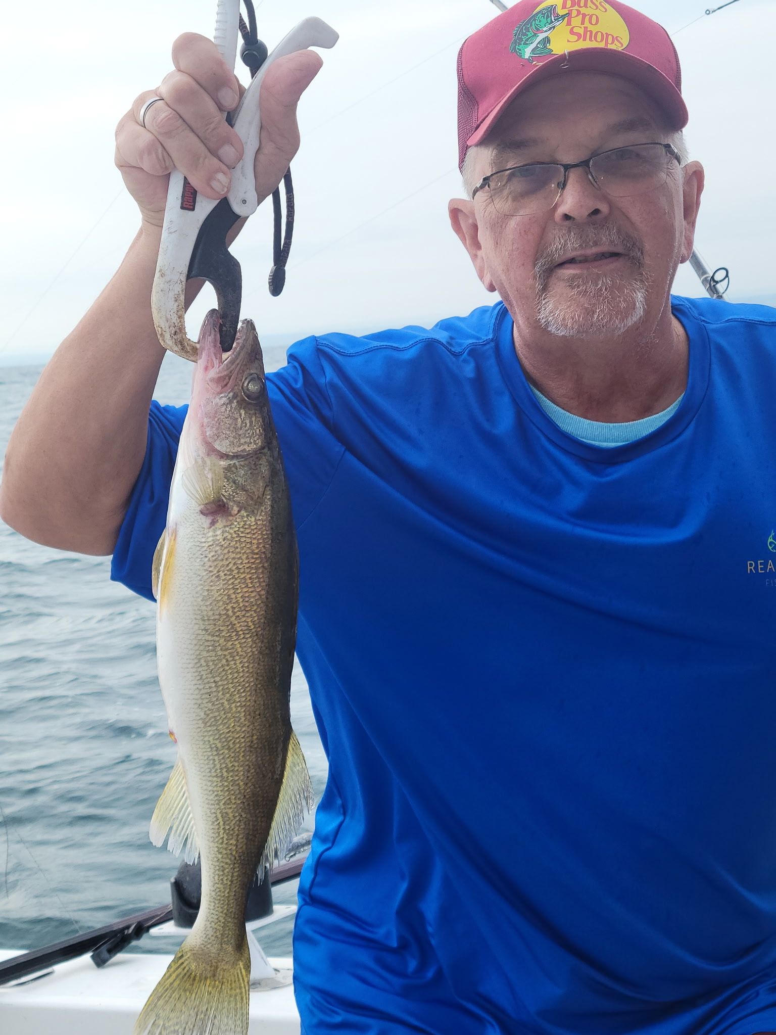 Freshly caught walleye being held up on fishing boat over water