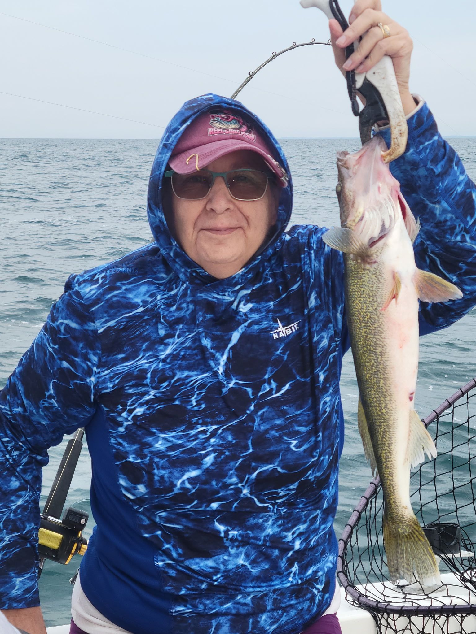 Fresh caught walleye being held up on fishing boat over water